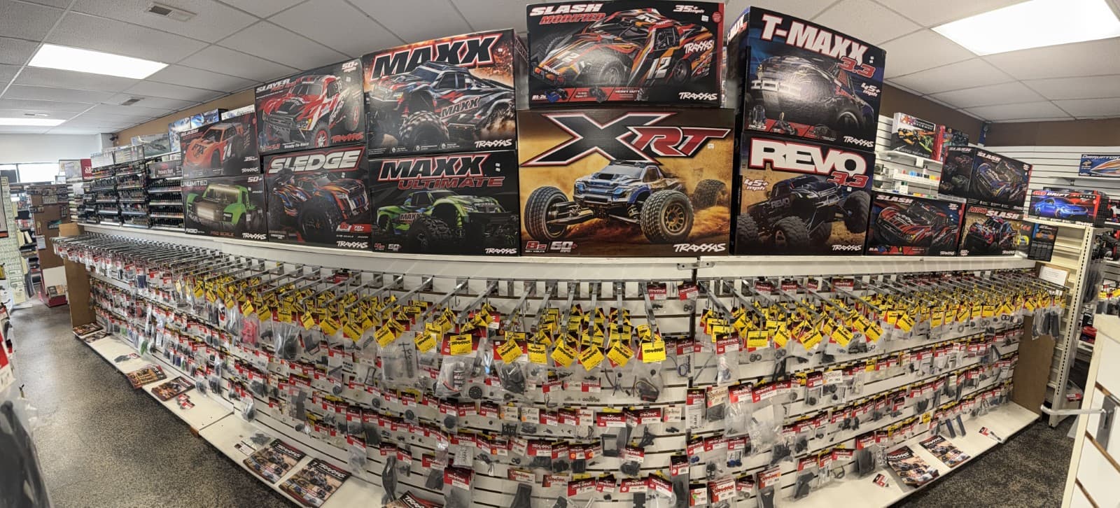 Traxxas RC car boxes displayed above a pegboard wall filled with numerous replacement parts.