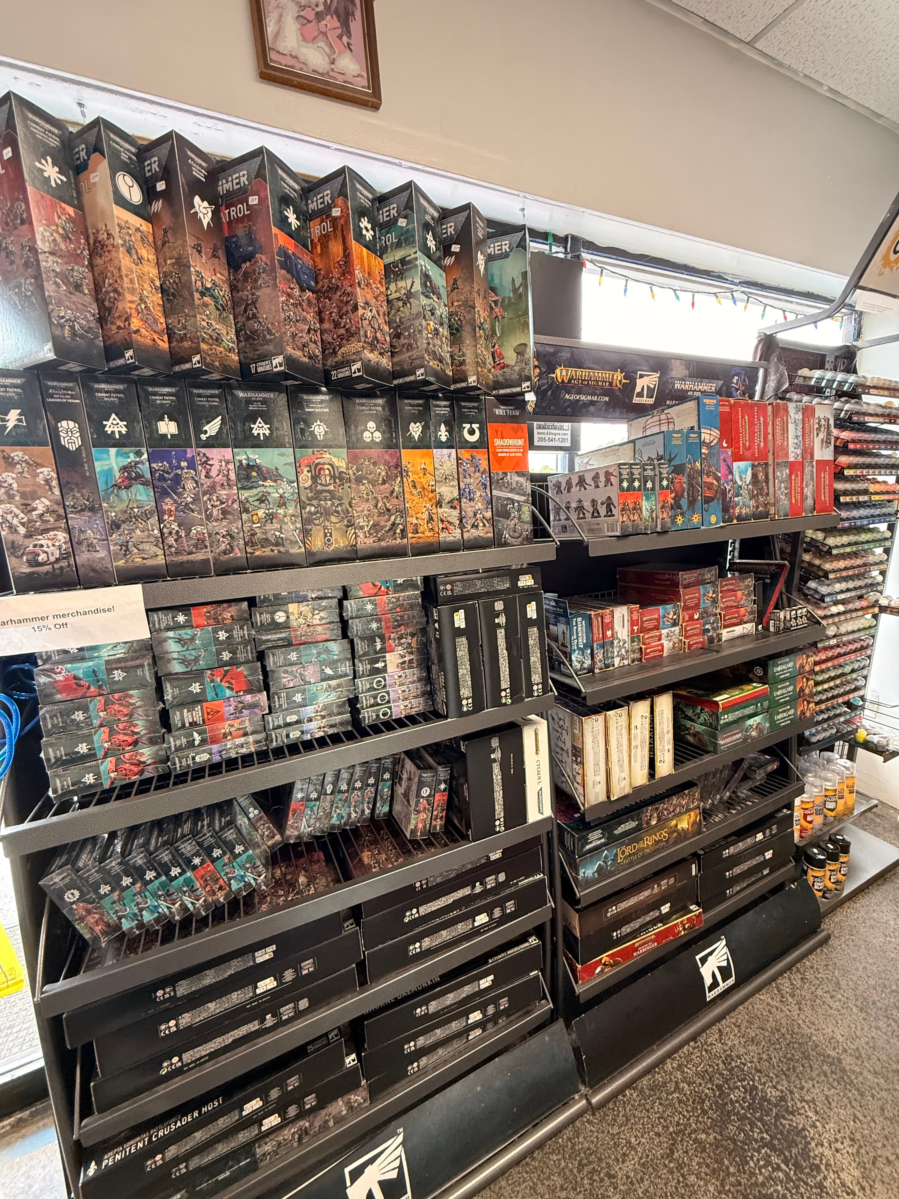 Shelves in a hobby store stocked with Warhammer boxed sets and tabletop gaming merchandise.