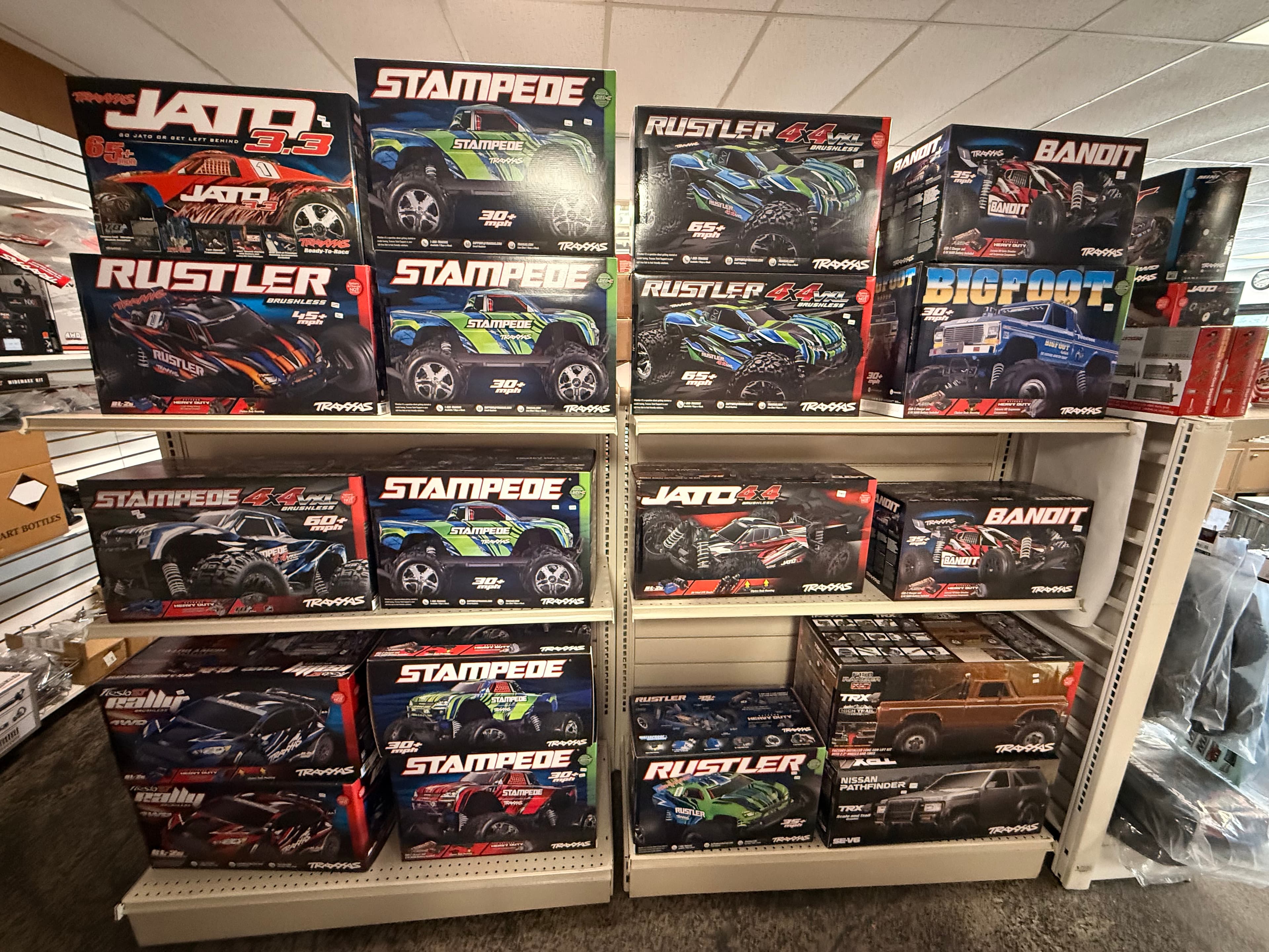 Shelves in a hobby shop stocked with various Traxxas remote-controlled car and truck boxes.